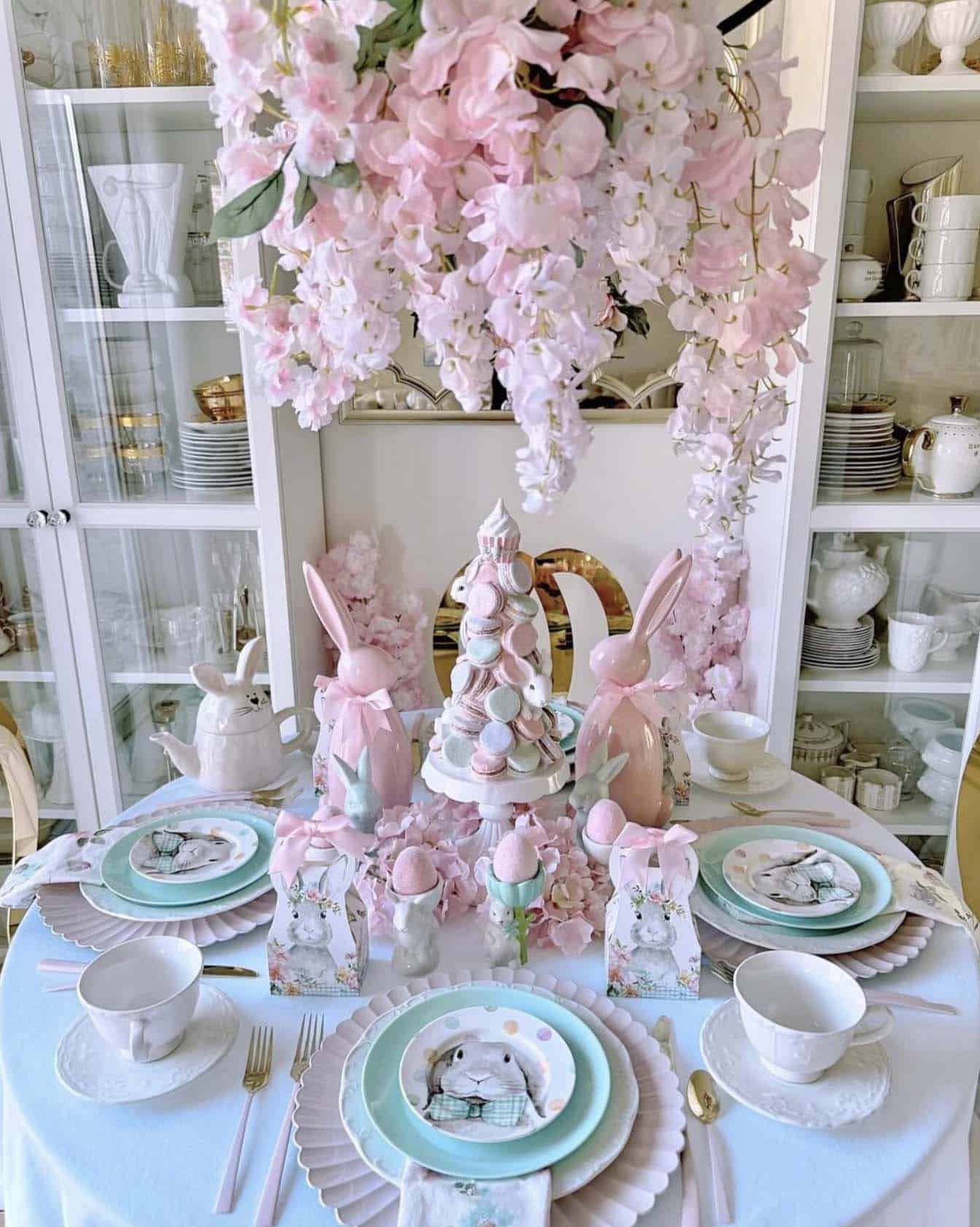 Easter dining table decor with pink flowers and pink bunnies and pink and blue plates 