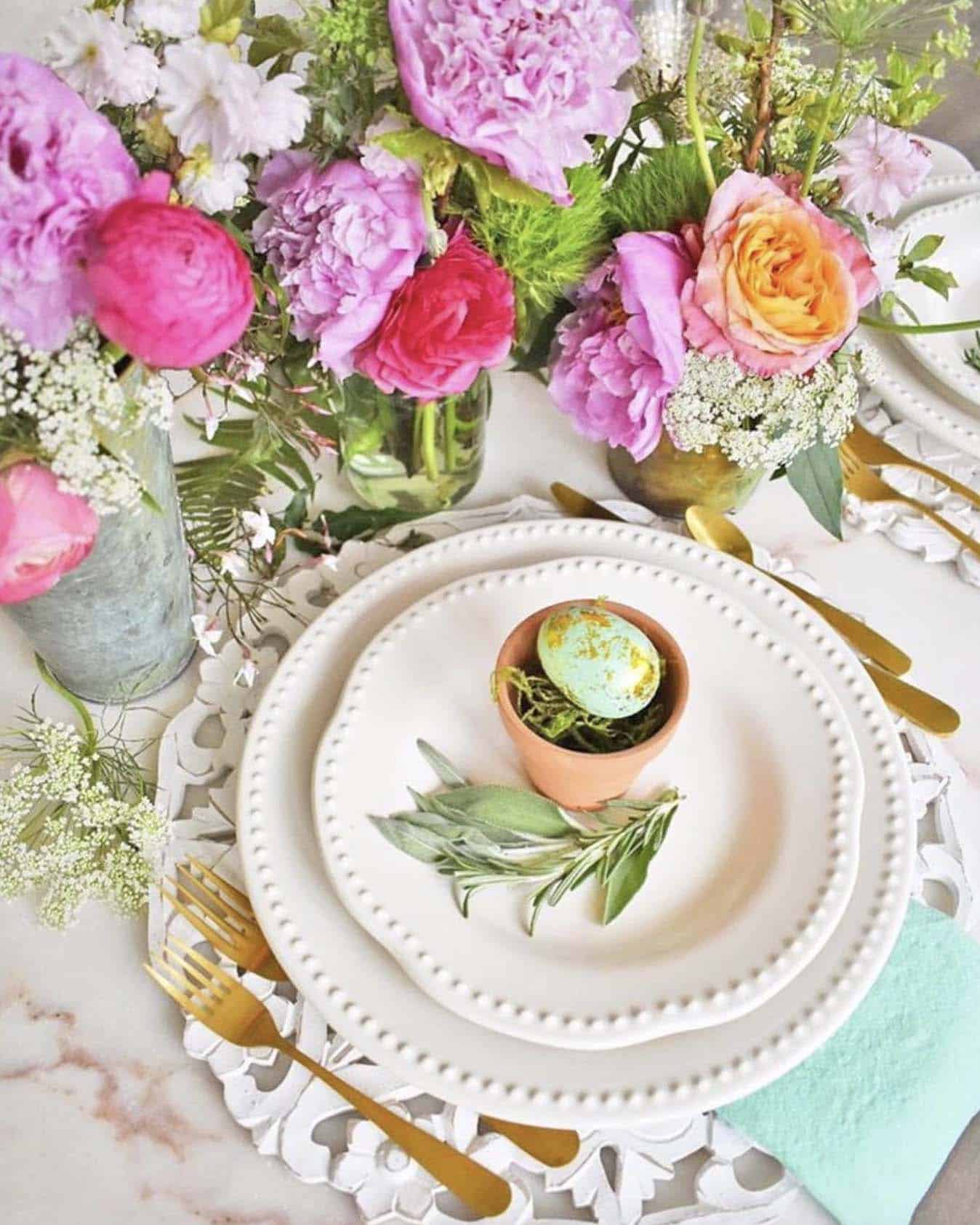 dining table place setting with layered plates topped with gold foil wrapped Easter eggs in a small terracotta pot