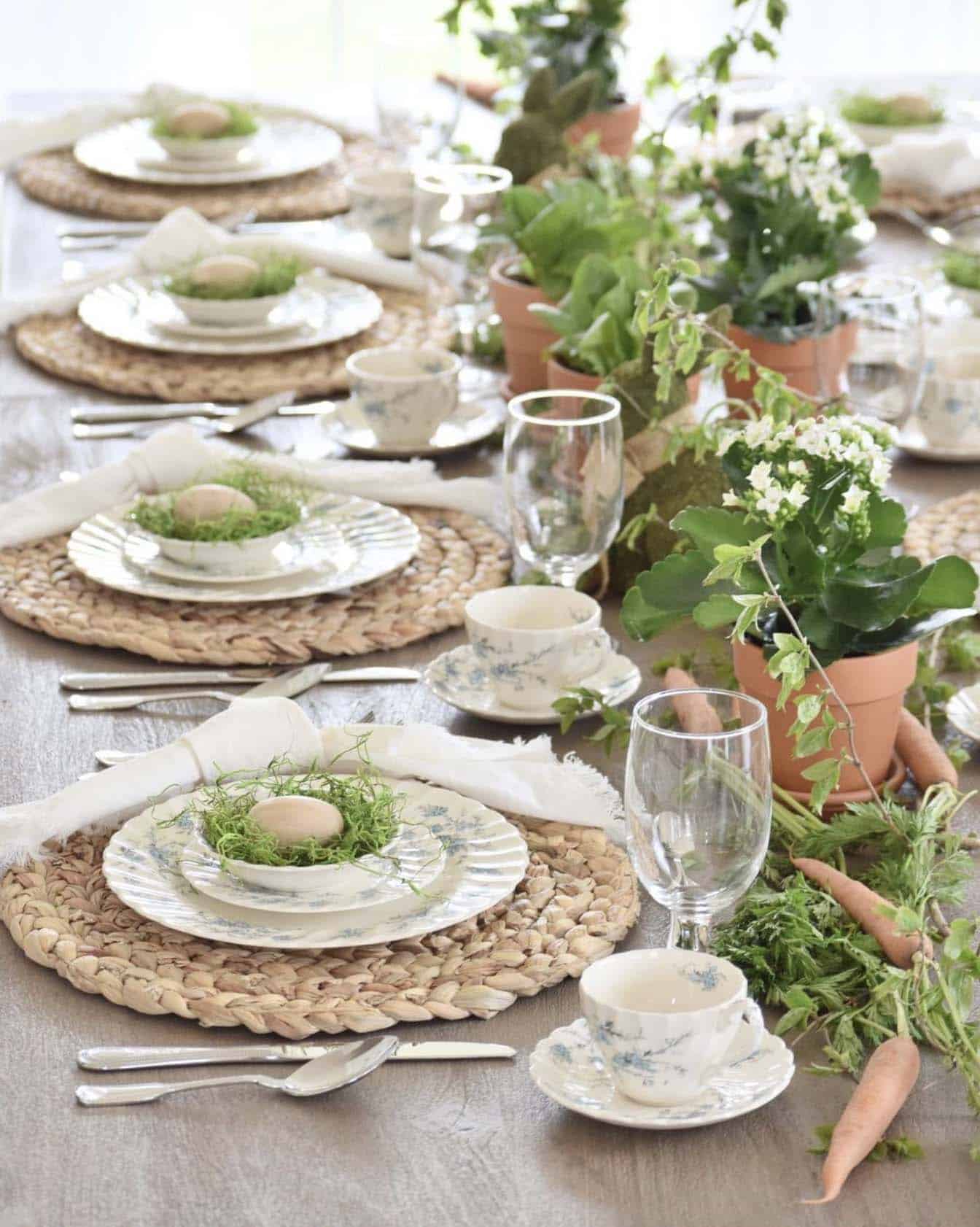 Easter tablescape with terracotta pots, blooming flowers, branches, moss, and wooden eggs