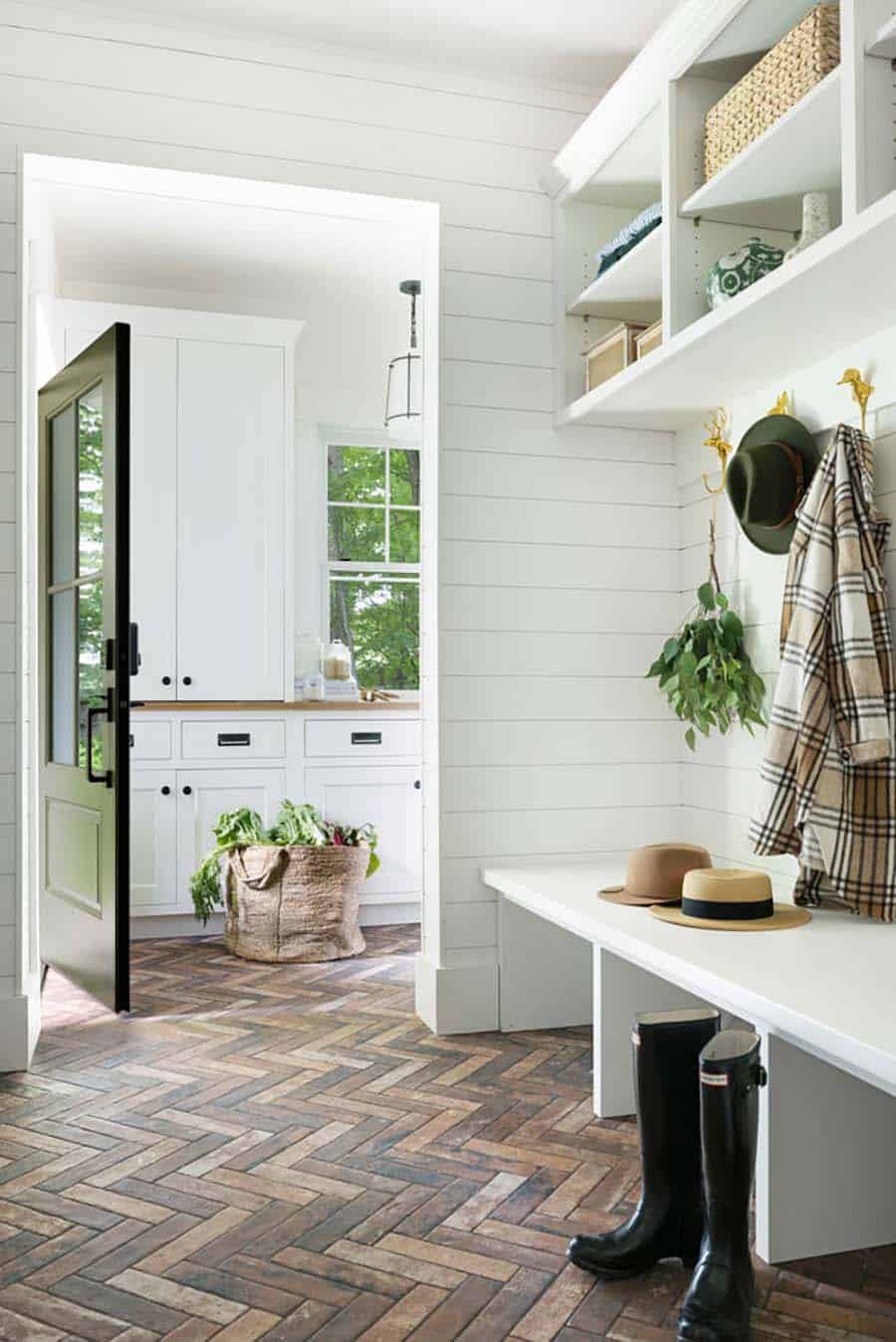 contemporary mudroom with a bench and brick herringbone flooring