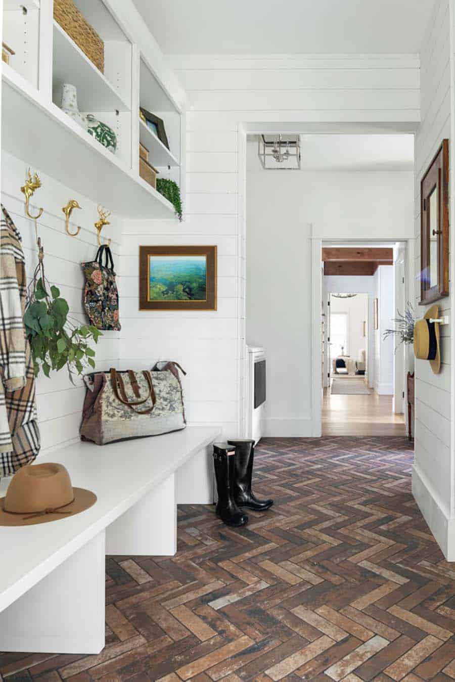 contemporary mudroom with a bench and brick herringbone flooring