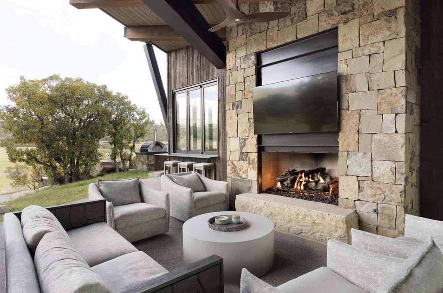 modern rustic covered outdoor living room with a fireplace