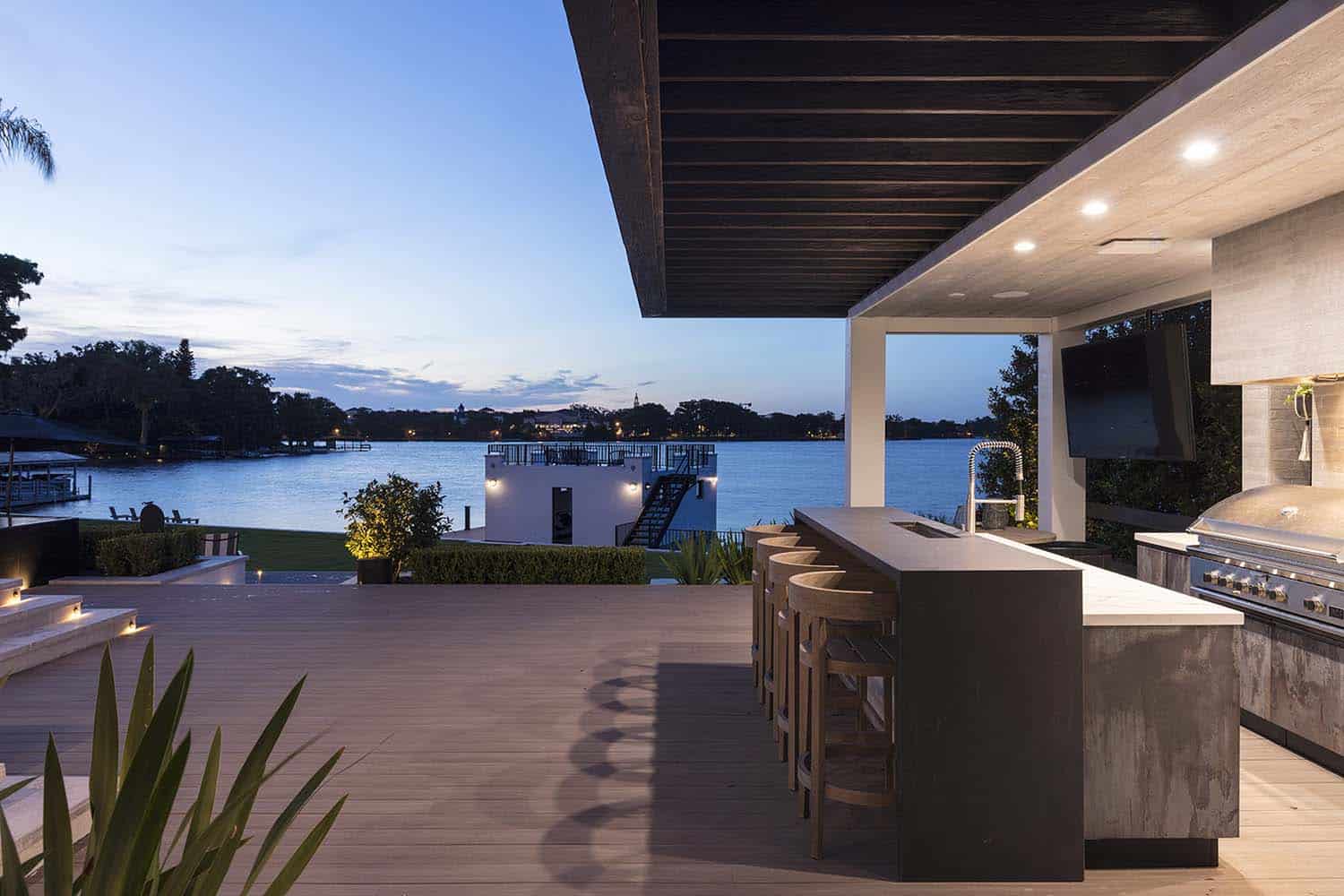 transitional style home outdoor covered patio with a kitchen and dining area at dusk