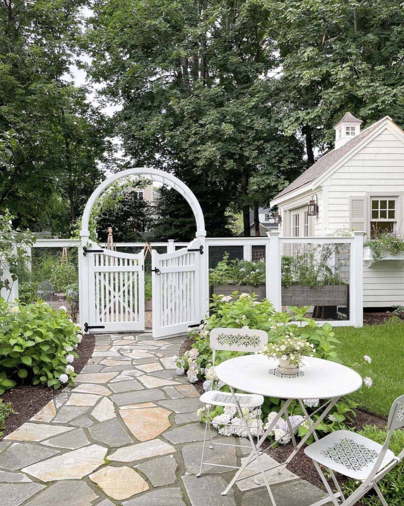 garden fence and arched trellis gate leads to backyard garden and home office shed