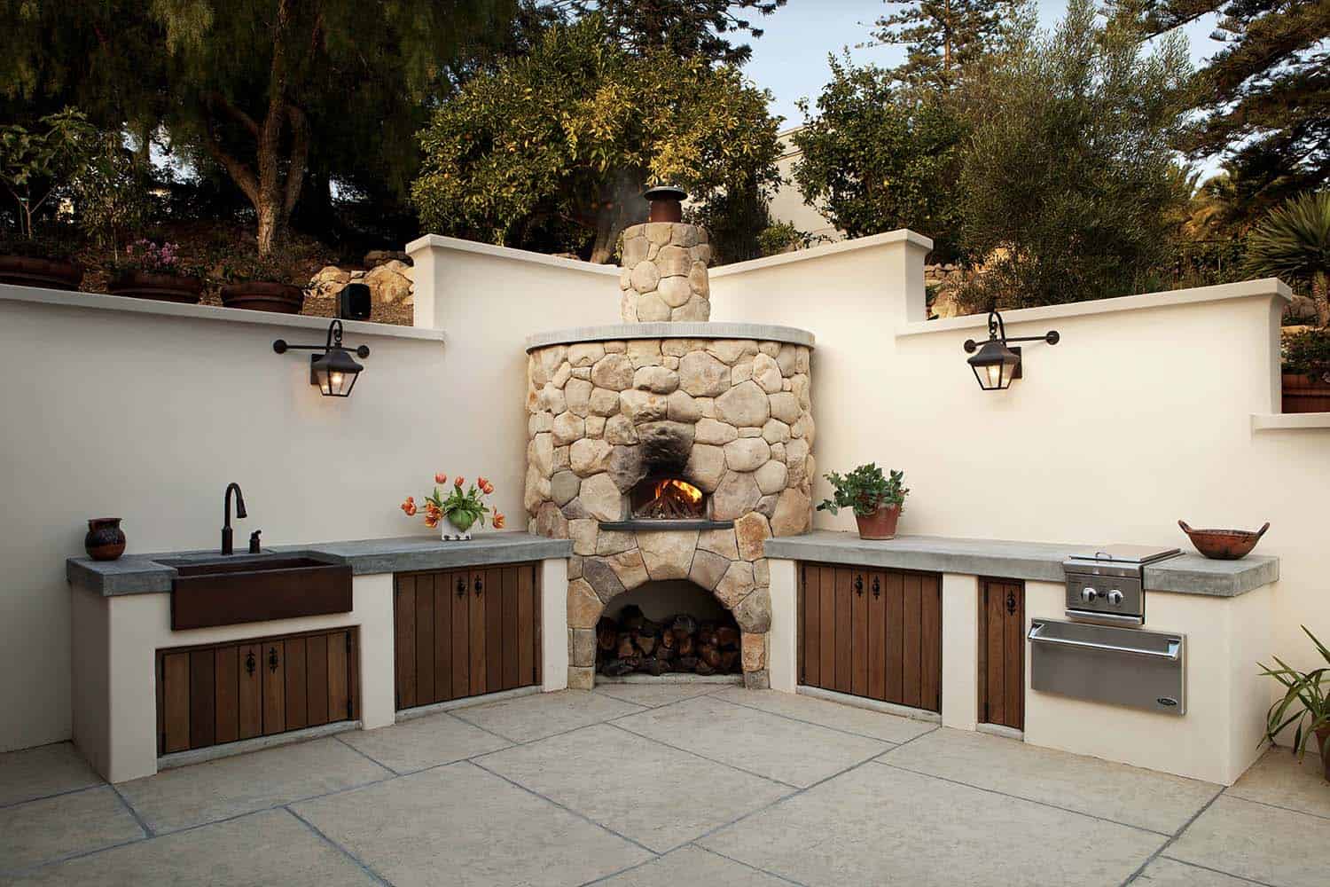 mediterranean style patio with an outdoor kitchen and pizza oven