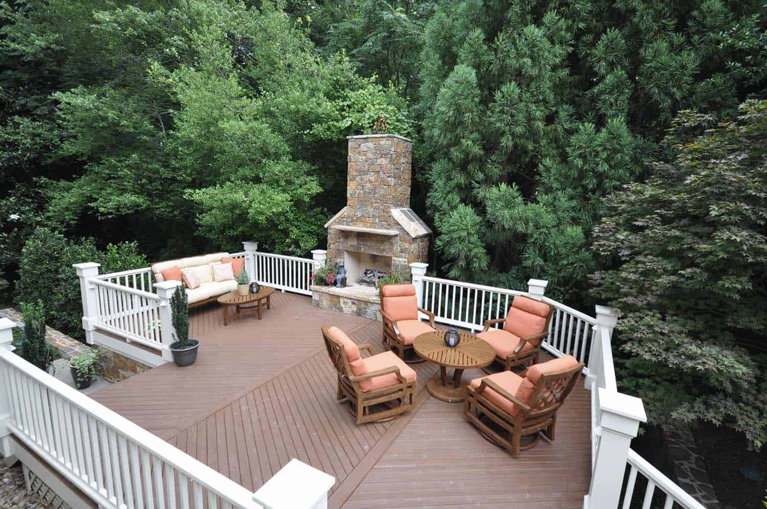 traditional deck with a fireplace and outdoor furniture with a backdrop of trees