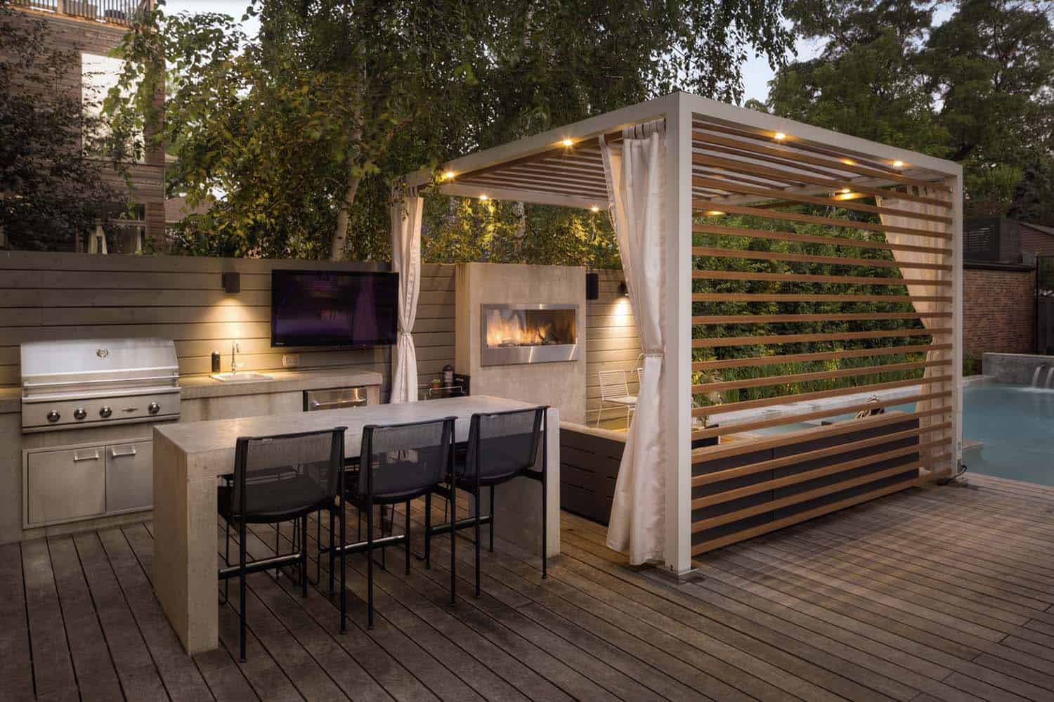 urban backyard deck with an outdoor kitchen and pergola with a fireplace