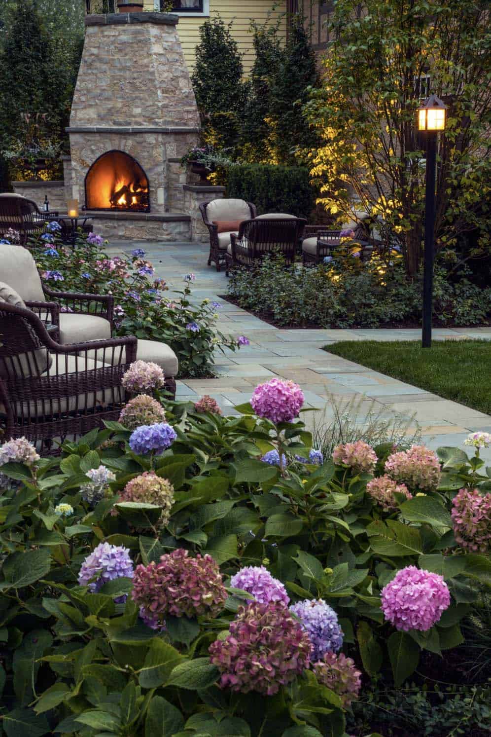 traditional fireplace with bluestone pavers, and lush landscaping