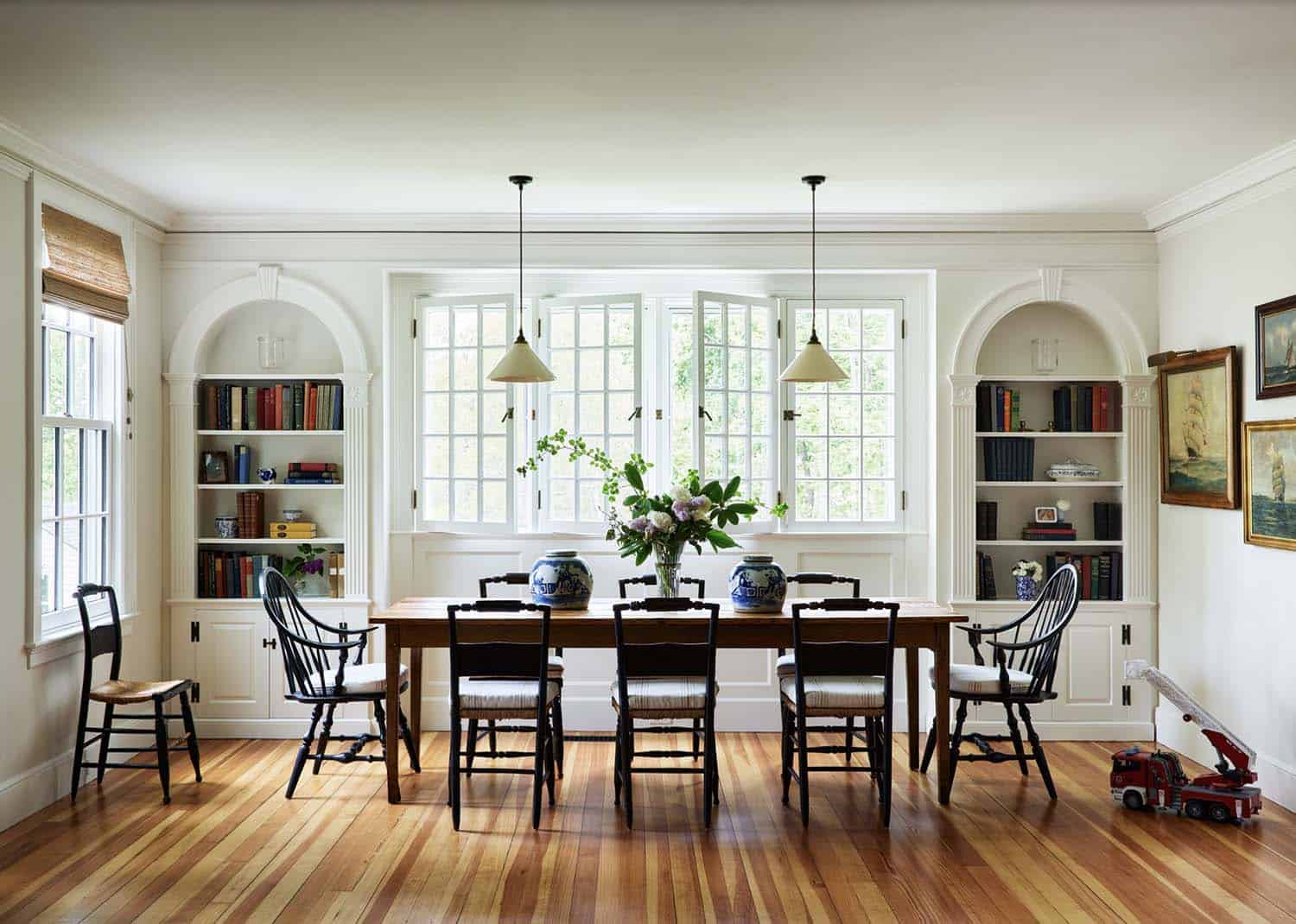 beach style dining room with built-in bookcases and paneled walls and windows