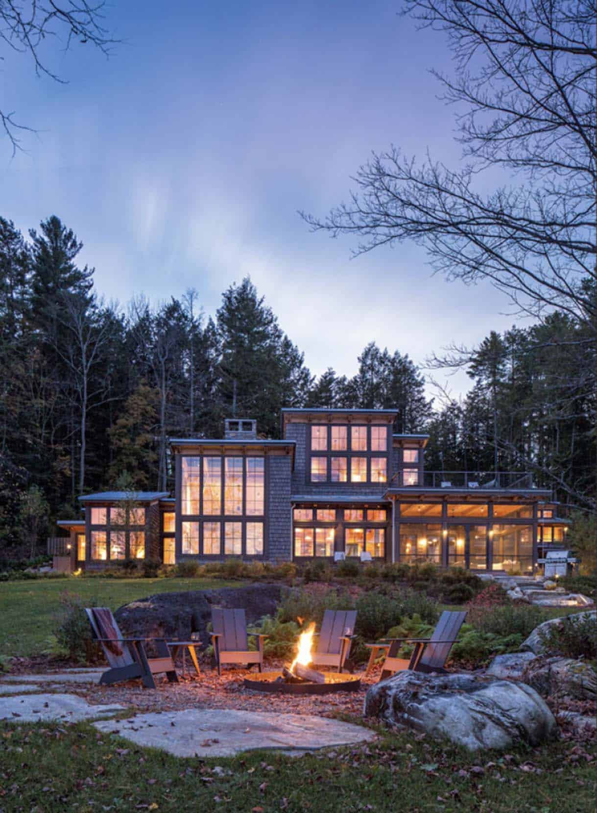 modern rustic lake house exterior with a fire pit at dusk