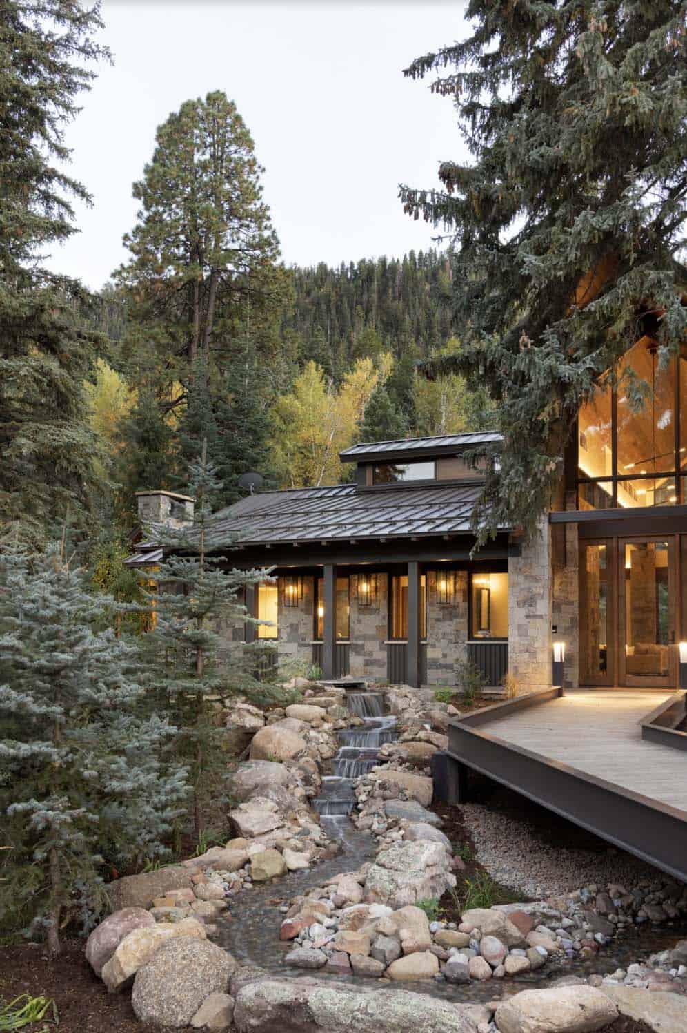 modern rustic mountain home exterior with a waterfall at dusk