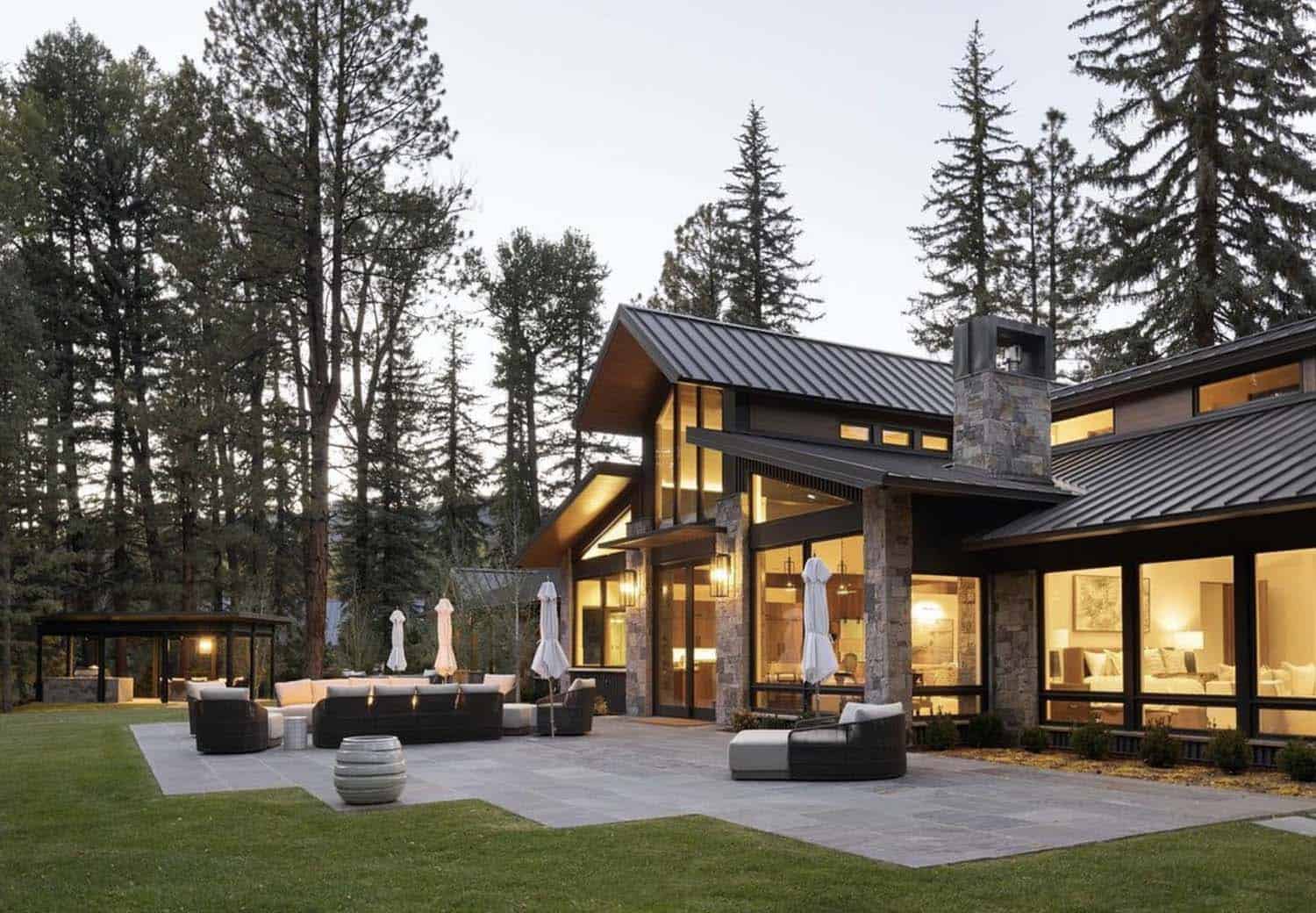 modern rustic mountain home exterior with a patio at dusk